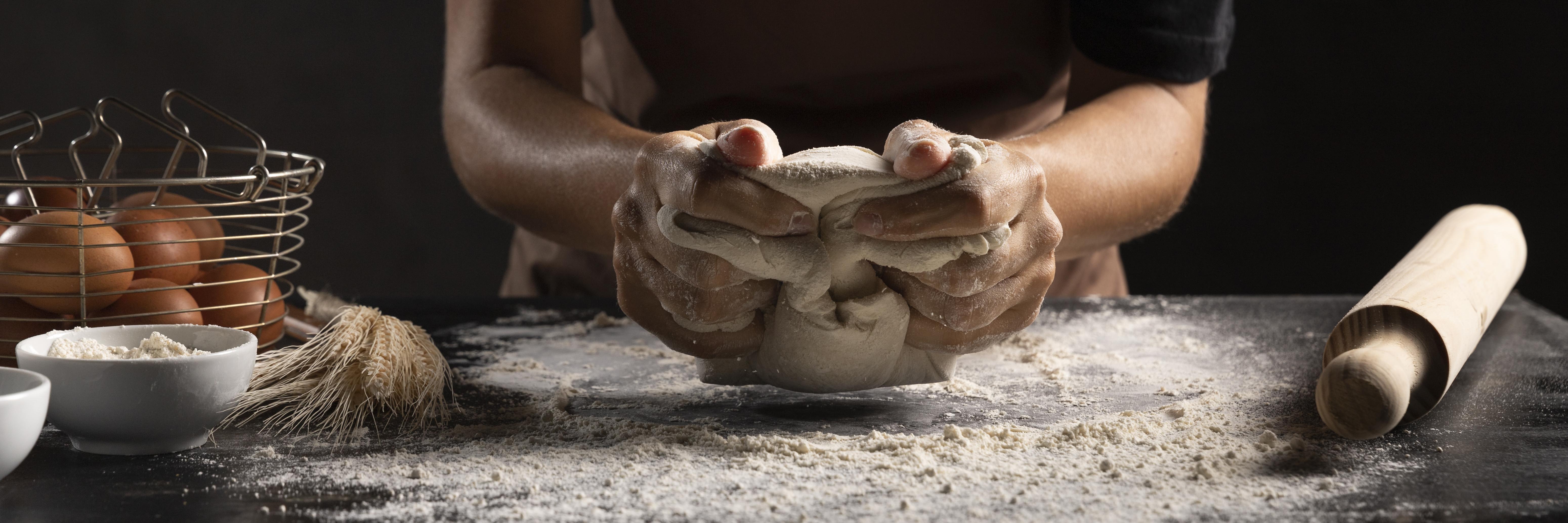 Baker using hands to knead dough.